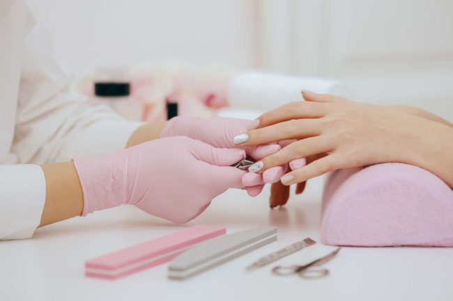 A nail artist carefully applies nail polish to a client's nails in a salon setting, using precise techniques.